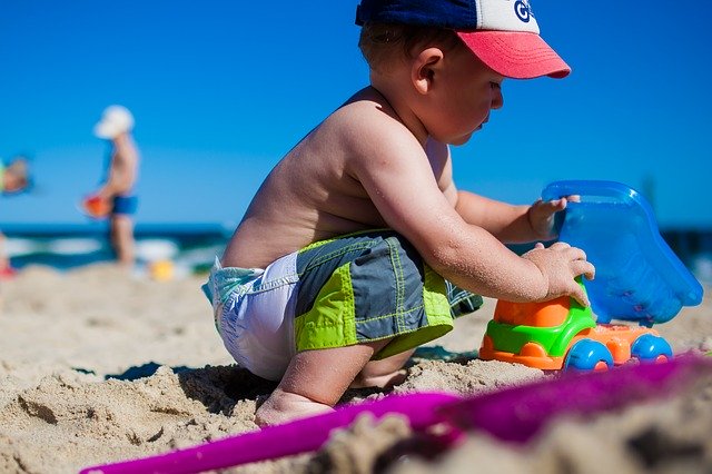 Dieťa sa hrá na pláži s formičkami v piesku.jpg
