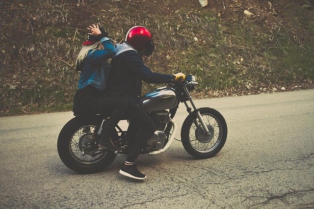 Chlapec a dievča s červenými prilbami na motorke